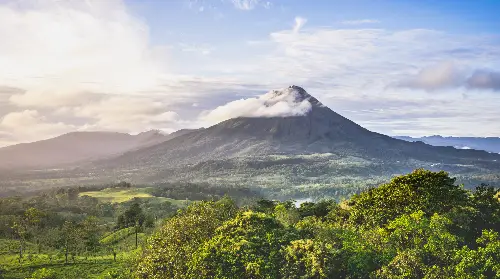 A mountain with trees and clouds in the background