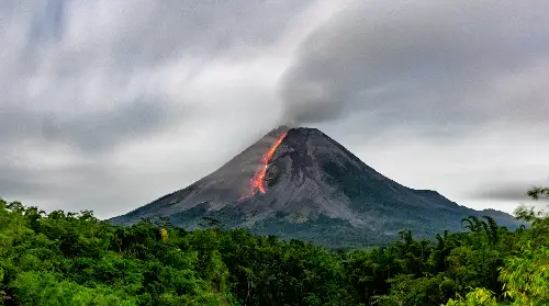 A very tall mountain with smoke coming from it.